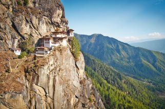 Das Tigers Nest schmiegt sich an den steilen Felsabhang vor einer offenen Berglandschaft