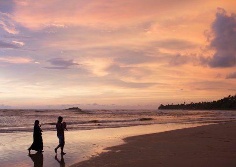 Am Strand den farbenfrohen Sonnenuntergang betrachten
